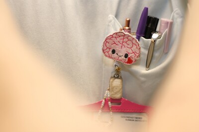 Anstecker an der Brusttasche in Form eines Gehirns mit Gesicht