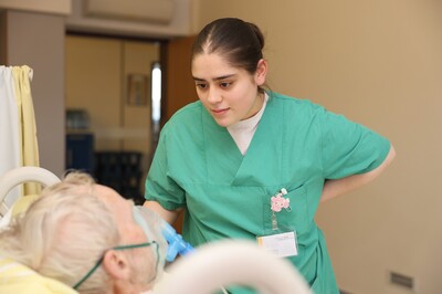 Pflege-Auszubildende versorgt Patienten am Bett