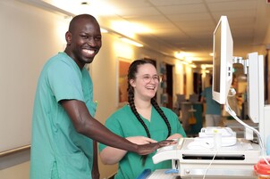 Zwei Pflege-Auszubildende am Computer auf dem Stationsflur